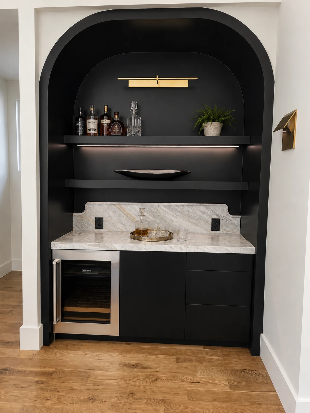 Custom arched wet bar with floating shelves and marble counter built by Innovations Carpentry